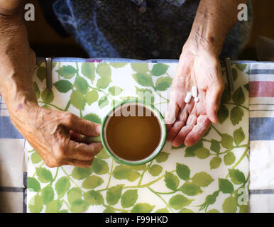 Close up della vecchia donna di mani pillole in cucina cucina Foto Stock