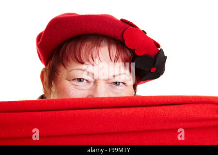 Senior donna nascosto dietro una sciarpa rossa Foto Stock