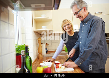 Il marito preparare i frutti di granola in cucina mentre la moglie è guardare Foto Stock