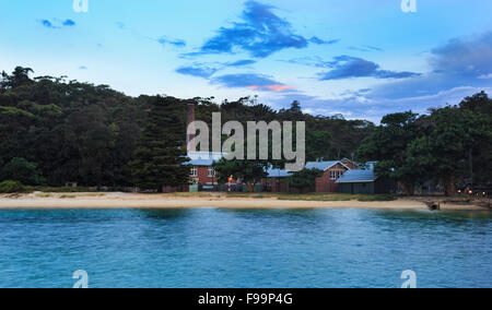 Spiaggia di quarantena del Sydney Harbour National Park al tramonto. Vista frontale da acque portuali verso edifici, caldaia house wit Foto Stock