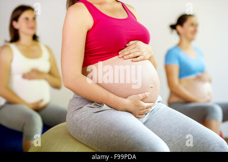 Giovani donne in stato di gravidanza facendo esercizio utilizzando una sfera di fitness Foto Stock