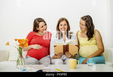 Tre donne in stato di gravidanza seduti sul divano e posa Foto Stock