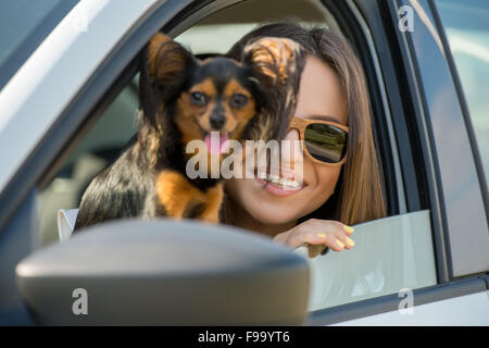 Donna e cane in auto sul viaggio estivo. Divertente cane in viaggio. Vacanza con il concetto di pet. Foto Stock