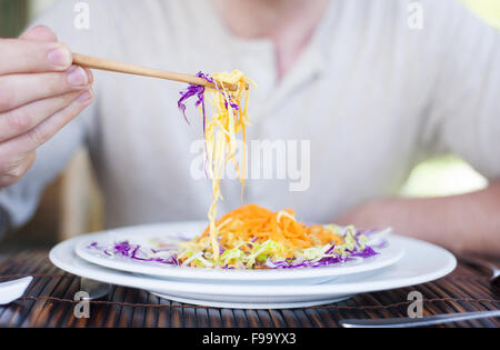 Close up di un uomo gustando un pasto con bacchette in ristorante vietnamita Foto Stock