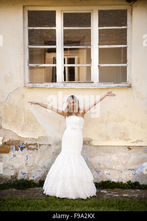 Bella bionda e giovane sposa in posa da casa vecchia Foto Stock