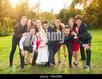 A piena lunghezza Ritratto di sposa giovane divertendosi con damigelle e groomsmen nel verde parco di sole Foto Stock