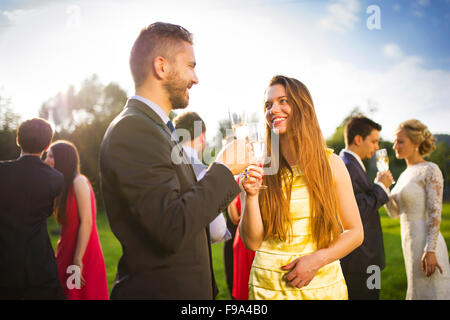 Gli ospiti dei matrimoni tintinnanti bicchieri al ricevimento di nozze al di fuori Foto Stock