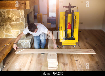 Giovani tuttofare installazione e misurando il legno compensato per pavimenti in legno Foto Stock