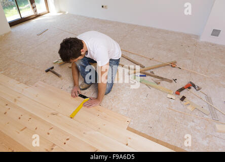 L'uomo la misura di pavimenti in legno nella nuova casa Foto Stock