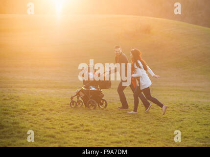 Felice e famiglia giovane con la PRAM durante la passeggiata nella natura Foto Stock