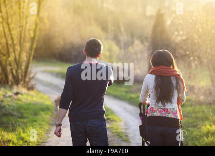 Felice e famiglia giovane con la PRAM durante la passeggiata nella natura Foto Stock