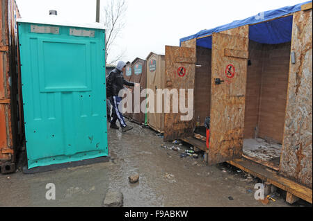 Fila di docce temporanee sporche e servizi igienici nel campo profughi Jungle a Calais, in una mattina piovosa inverno. Le docce corrono solo su acque fredde e i servizi igienici sono sporchi perché non vengono puliti abbastanza spesso. Foto Stock