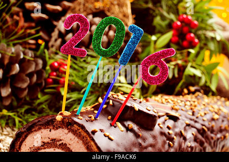 Un registro di yule cake, tradizionale del tempo di Natale, guarnita con scintillante di numeri di differenti colori che formano il numero 2016, come t Foto Stock