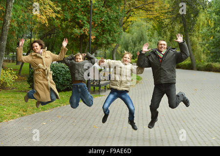 Famiglia jumping in autunno park Foto Stock