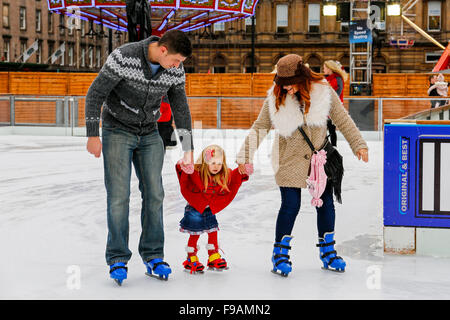 Glasgow, Scotland, Regno Unito. 15 Dic, 2015. Glasgow annuali di 'Natale sul ghiaccio' outdoor spettacolare pista di pattinaggio su ghiaccio in George Square nel centro della città attrae i pattinatori di tutte le età e abilità. Coloro che sono un po' incostante sul ghiaccio ottieni un qualche aiuto da parte di genitori e parenti. Un modo divertente per avere una pausa da shopping di Natale. Credito: Findlay/Alamy Live News Foto Stock