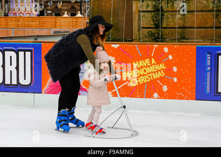 Glasgow, Scotland, Regno Unito. 15 Dic, 2015. Glasgow annuali di 'Natale sul ghiaccio' outdoor spettacolare pista di pattinaggio su ghiaccio in George Square nel centro della città attrae i pattinatori di tutte le età e abilità. Coloro che sono un po' incostante sul ghiaccio ottieni un qualche aiuto da parte di genitori e parenti. Un modo divertente per avere una pausa da shopping di Natale. Credito: Findlay/Alamy Live News Foto Stock