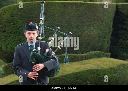 Teen boy riproduzione di cornamuse fuori Crathes Castle in Aberdeenshire, Scozia. Foto Stock