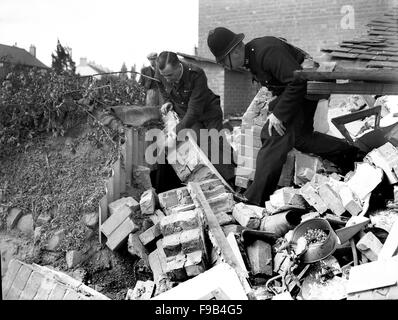 Un poliziotto e precauzioni di raid aereo operaio controllo per i superstiti in un rifugio di Anderson in Coventry seguenti Blitz tedesco della città 1940 Foto Stock