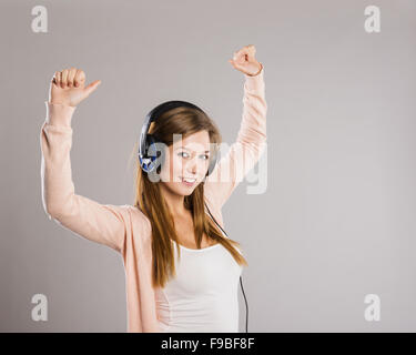 Attraente ragazza con cuffie su sfondo grigio Foto Stock