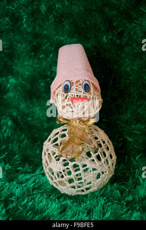 Toy pupazzo di neve realizzato dalla sfera di filato in rosa hat con cordone blu su sfondo verde Foto Stock