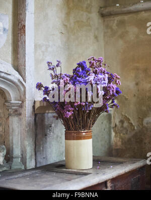 Vaso di terracotta con viola e spostare i fiori secchi in una chiesa o cappella Foto Stock