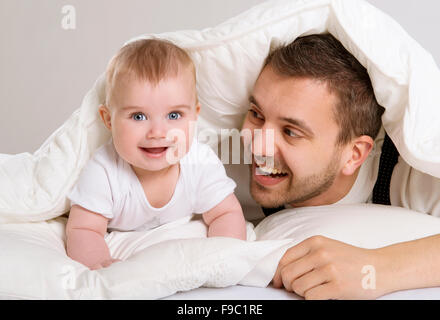 Giovane padre sta giocando con il bambino nel letto Foto Stock