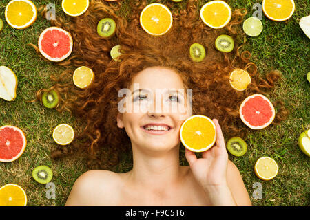 Ragazza con frutta sdraiati sull'erba Foto Stock