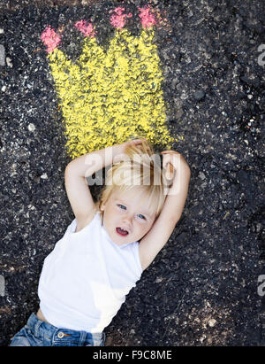 Carino bambino dipinto con colori intensi e i gessi sulla strada Foto Stock