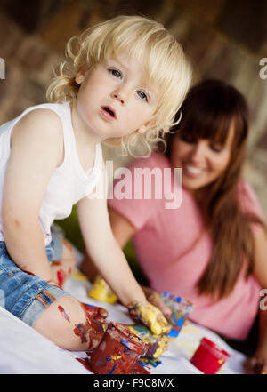 Carino bambino dipinto con colori vivaci in giardino Foto Stock