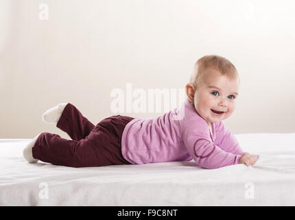 Sweet Little baby è sdraiato sul materasso in studio Foto Stock