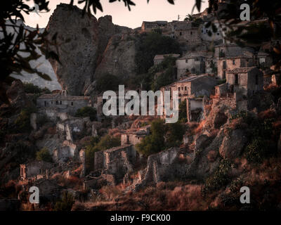 Il villaggio abbandonato di Pentedattilo al tramonto incorniciato da sfocato ulivo rami, Calabria, Italia. Foto Stock