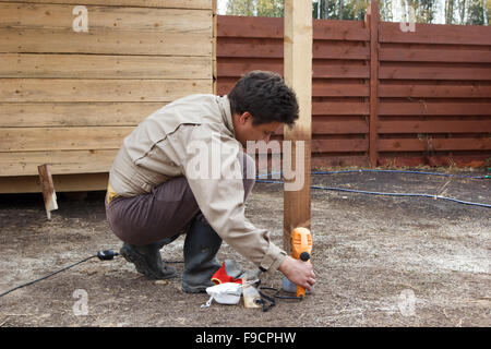 L'uomo la preparazione di pistola a spruzzo per la verniciatura di struttura in legno Foto Stock