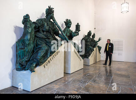 Monaco di Baviera, Germania. Xvi Dec, 2015. Un uomo cammina oltre i quattro grandi sculture in bronzo Fortitudo (L-R), Temperanta, Prudentia e Justitia in bronzo nella raccolta della Residenz di Monaco di Baviera, Germania, 16 dicembre 2015. Le figure sono state precedentemente visualizzato all'aperto e sono ora stati portati all'interno a causa di un aumento dei carichi inquinanti e la corrosione. Dal 17 Dicembre 2015 fino al 14 febbraio 2016, una collezione unica di sculture in bronzo tra il XVI e il XVII secolo sarà mostrato nell'ala presso l'imperatore del Cortile della Residenz di Monaco di Baviera. Foto: Matthias esitano di fronte/dpa/Alamy Live News Foto Stock