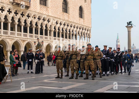 Venezia, Piazza San Marco. I soldati italiani marzo passato il Palazzo dei Dogi a partecipare all'abbassamento della cerimonia della bandiera al tramonto Foto Stock