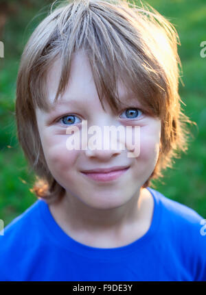 Ritratto di un ragazzo con i capelli biondi e parte superiore blu sorridente Foto Stock