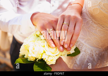 Le mani e gli anelli sul mazzo di nozze close up Foto Stock