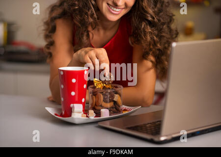 Biscotti di Natale sono un modo meraviglioso per godere lo spirito della stagione. Primo piano su sorridente giovane donna avente una tazza di acqua calda chocol Foto Stock