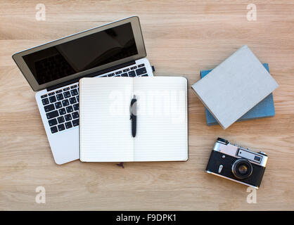 Laptop, cinepresa, Blocco note con penna e un paio di libri sul tavolo di legno. Foto Stock