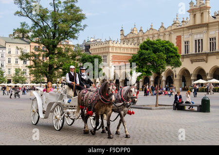 I turisti city tour in carrozza al di fuori del XIII secolo Sukiennice (il panno Hall o trasportatori' Hall) nella Piazza del Mercato di Cracovia in Polonia Foto Stock