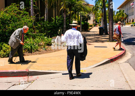 Gli uomini indossano diversi livelli di abbigliamento da pantaloncini e maglietta per un vestito e un cappello di Panama a Santa Barbara in California Foto Stock