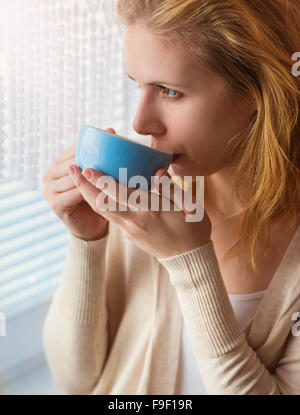 Bella donna sorseggiando il caffè dalla sua tazza Foto Stock