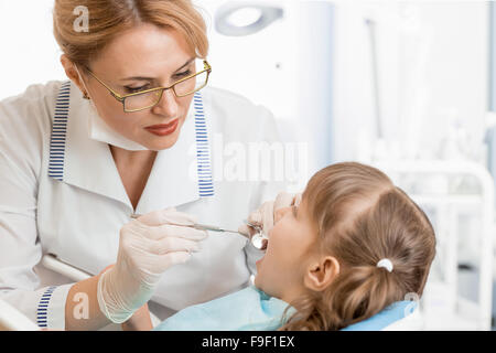 Dentista donna esaminando kid paziente in ufficio Foto Stock
