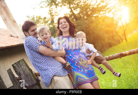 Felice giovane famiglia di trascorrere del tempo insieme e divertirsi nella parte anteriore di una vecchia casa di campagna. Foto Stock