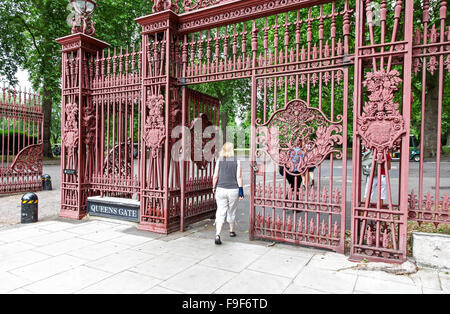 Una donna a piedi attraverso il ferro battuto cancelli di ingresso al Kensington Palace Gardens a Londra REGNO UNITO Foto Stock