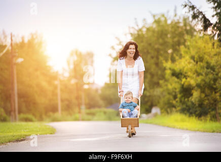 Felice giovane madre giocando con suo figlio al di fuori sulla strada di un villaggio Foto Stock