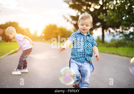 Carino piccolo ragazzi giocare e divertirsi al di fuori su una strada Foto Stock