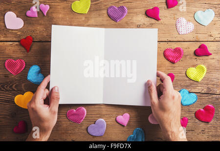 Svuotare il foglio di carta e tessuto colorato cuori. Studio shot su sfondo di legno. Foto Stock