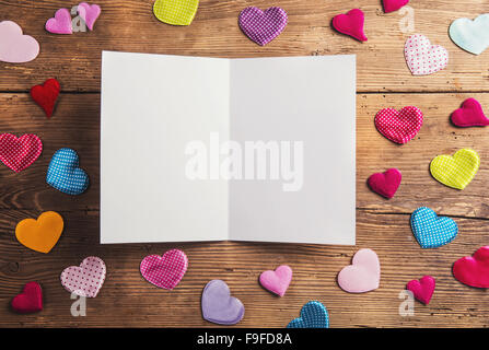 Svuotare il foglio di carta e tessuto colorato cuori. Studio shot su sfondo di legno. Foto Stock