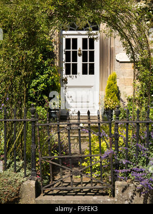 Regno Unito, Inghilterra, Derbyshire, Hartington, ferro vecchio cancello del giardino con parcheggio non notare che conduce al bianco dello sportello anteriore Foto Stock