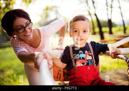 Felice giovane madre con suo figlio in un parco giochi per bambini Foto Stock